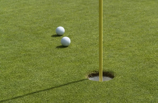Hole a golfové míčky v zelené zpět — Stock fotografie