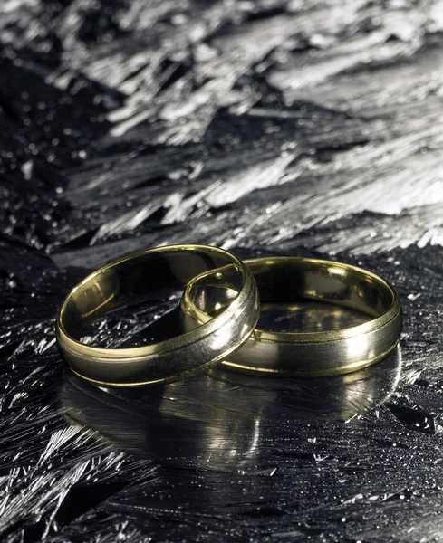 Two golden wedding rings on ice surface — Stock Photo, Image