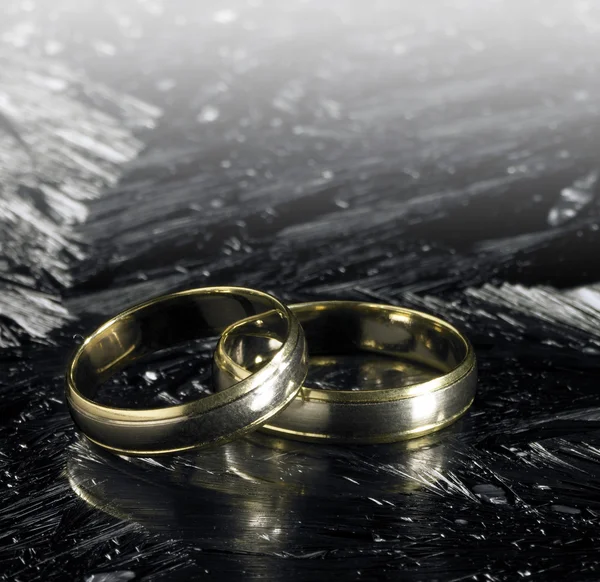Two golden wedding rings on ice surface — Stock Photo, Image