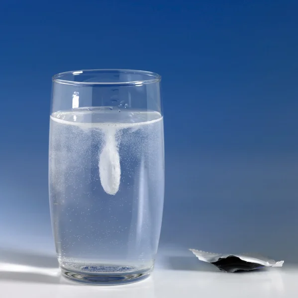 Disolver la tableta de fizzy en un vaso de agua — Foto de Stock