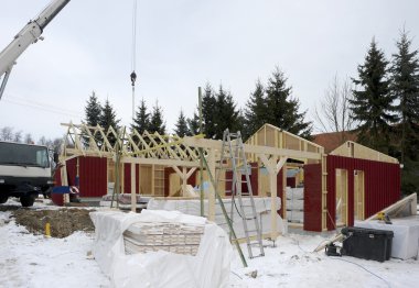 Wooden house construction at winter time clipart