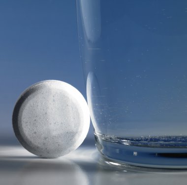 Fizzy tablet beside a glass of water clipart