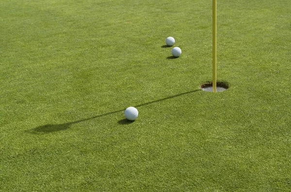 Buraco e bolas de golfe em verde de volta — Fotografia de Stock