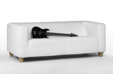 Black bass guitar on white couch clipart