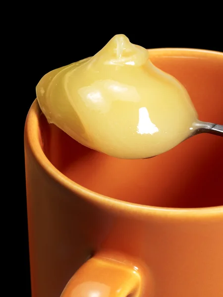 Cup and honey spoon — Stock Photo, Image