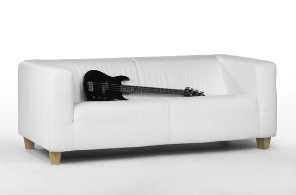 Schwarze Bassgitarre auf weißem Sofa — Stockfoto