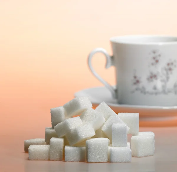 Cumulo di zucchero grumo e tazza di caffè in luce calda — Foto Stock