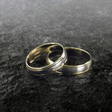 Two golden wedding rings on stone surface clipart