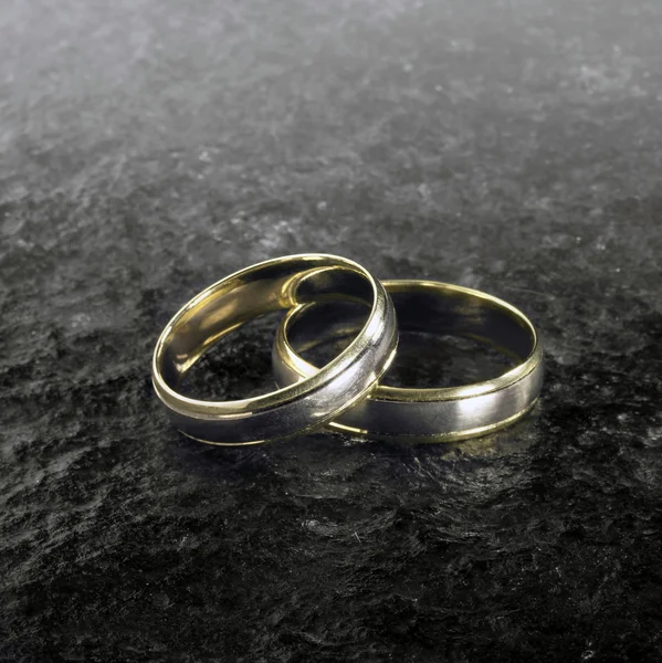 Two golden wedding rings on stone surface — Stockfoto