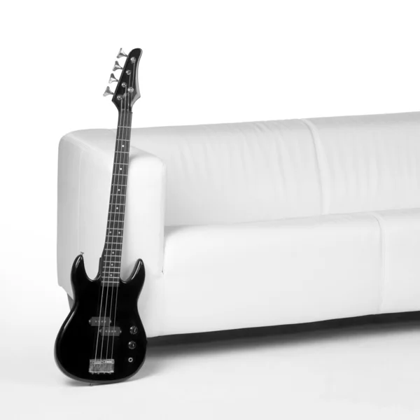Gitara basowa czarna i Biała kanapa — Zdjęcie stockowe