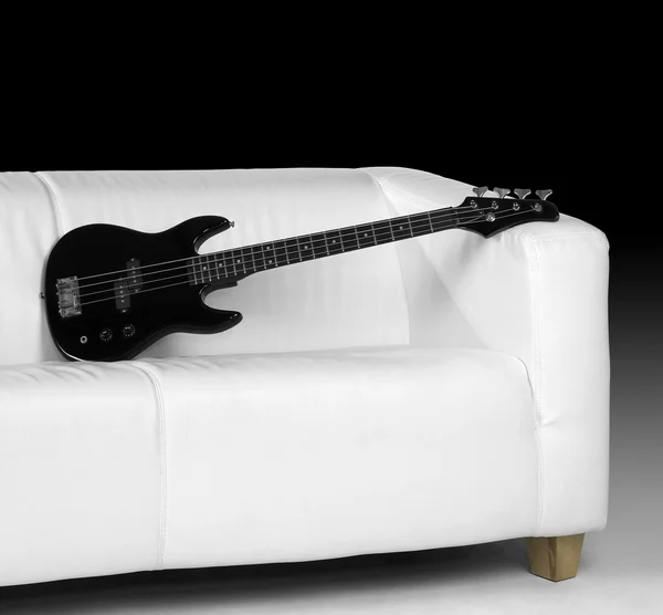 Gitara basowa czarna i Biała kanapa — Zdjęcie stockowe
