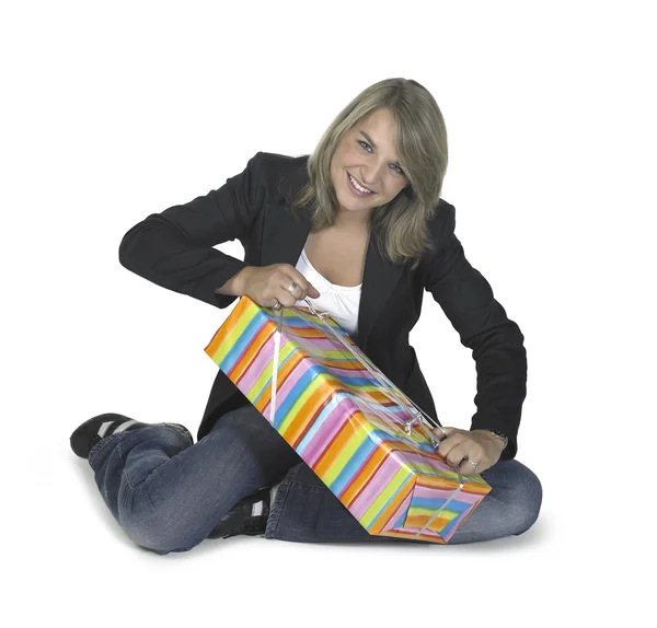 Sitting girl unwrapping a present Stock Image
