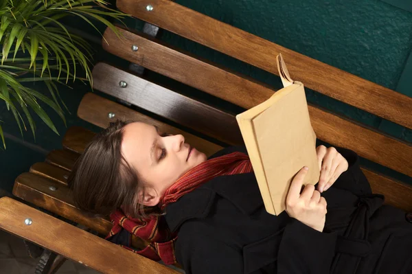 Junge Frau liegt auf Bank und liest — Stockfoto