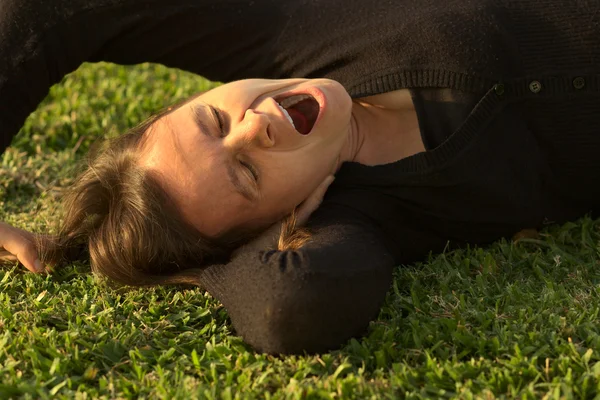 Mujer joven bostezando en la hierba — Foto de Stock