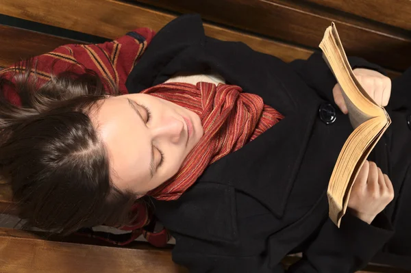 Junge Frau liegt auf Bank und liest — Stockfoto
