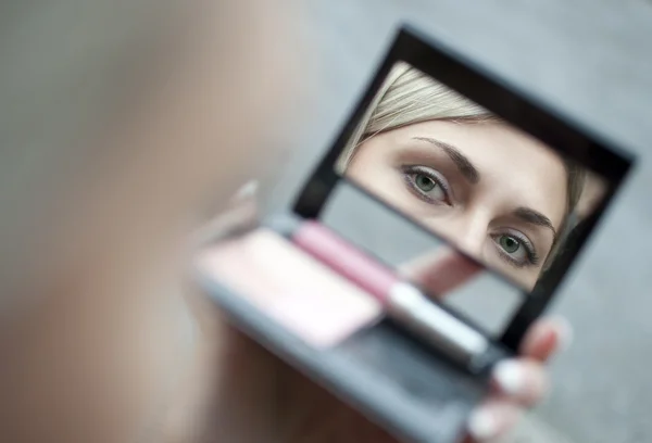 Jovem mulher olhando no espelho cosmético — Fotografia de Stock