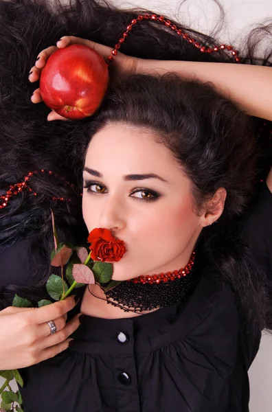 Schöne Brünette mit rotem Apfel und scharlachroter Rose — Stockfoto