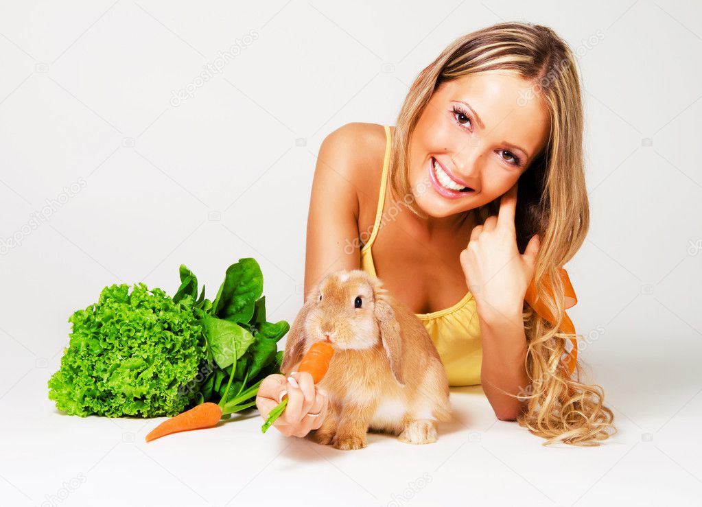 Pretty cheerful girl feeding a rabbit