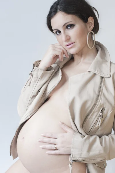 Stylish pregnant with earrings and beige jacket on white backgro — Stock Photo, Image