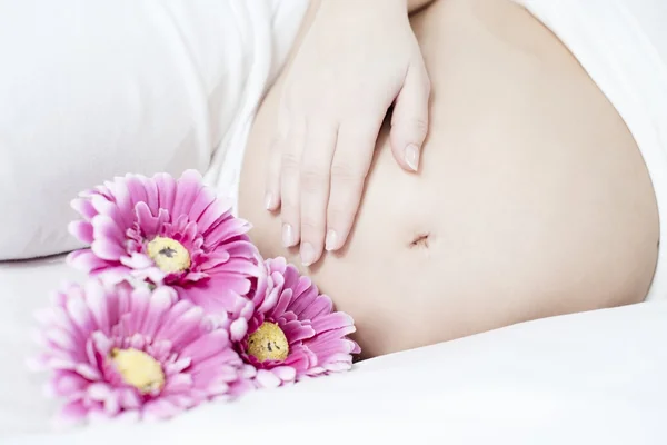 Młoda kobieta w ciąży z kwiatami — Zdjęcie stockowe