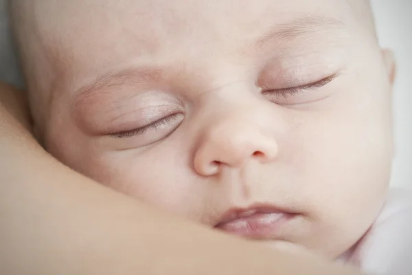 Pasgeboren slapen op de schouder van de moeder Stockfoto