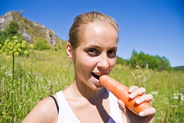 Lány eszik egy sárgarépa. — Stock Fotó