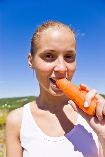 Lány eszik egy sárgarépa. — Stock Fotó