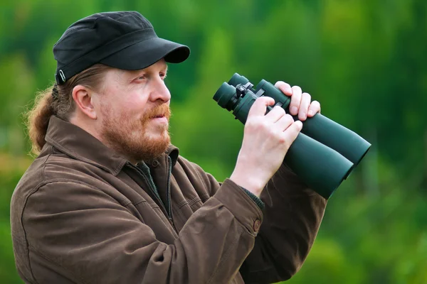 A bearded man with binoculars. — Stock Photo, Image