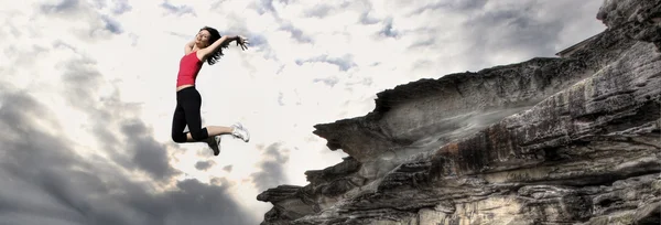 Девушка прыгает со скалы — стоковое фото