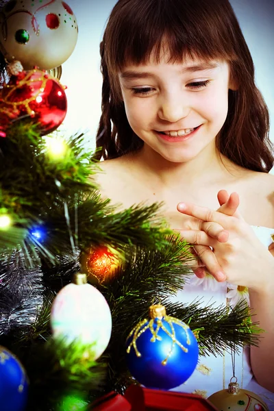 Lilla leende flicka under en julgran — Stockfoto