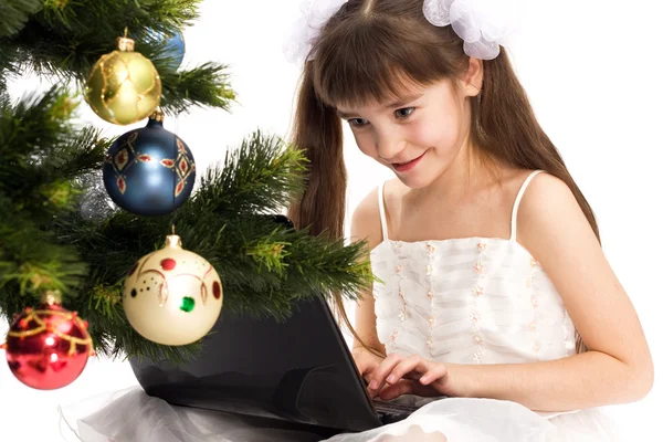 Little smiling girl looks at her laptop computer — Stock Photo, Image