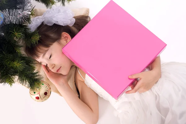 Hübsches kleines Mädchen schläft unter einem Weihnachtsbaum mit Geschenk — Stockfoto