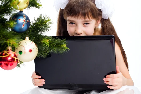 Liten leende flicka med bärbar dator — Stockfoto