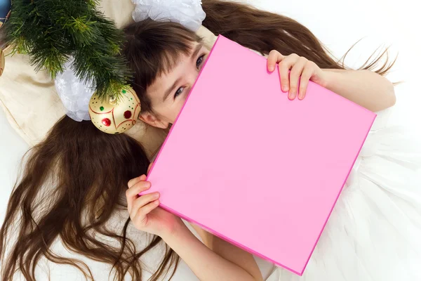 Niña bonita acostada bajo un árbol de Navidad con regalo Imagen de stock