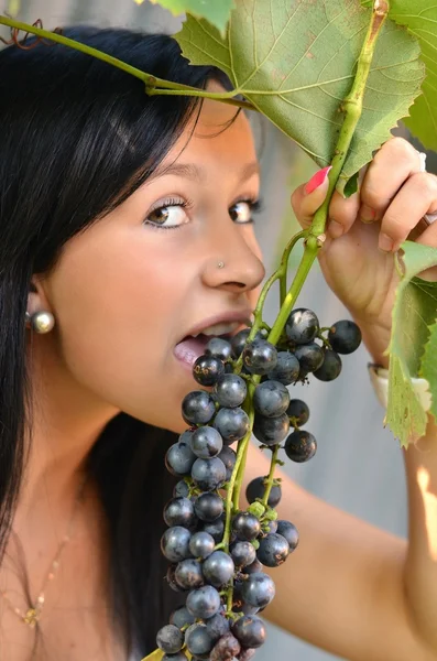 Beautiful woman with perfect hair and skin eating grapes. — Stock Photo, Image