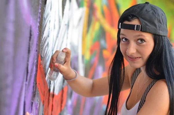Meisje tegen een muur met graffiti — Stockfoto