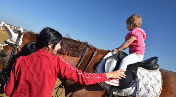 Muito pequena menina em seu cavalo preto — Fotografia de Stock