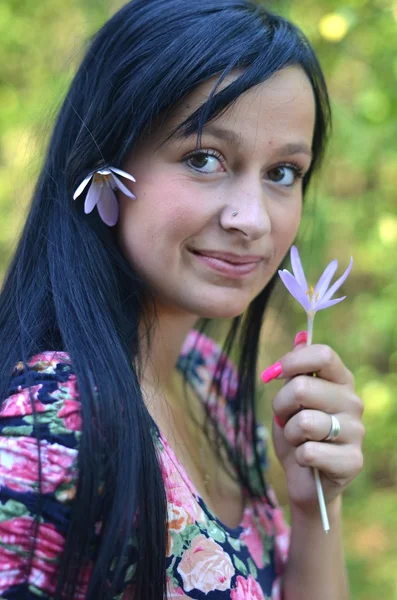 Beautiful young brunette woman with flower in her hair — Stock Photo, Image