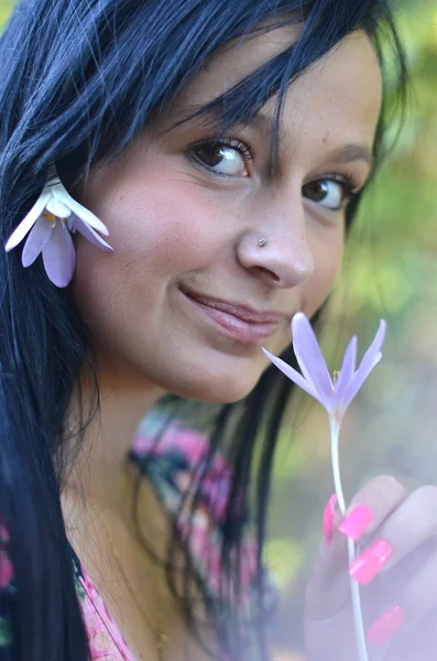 Beautiful young brunette woman with flower in her hair — Stock Photo, Image