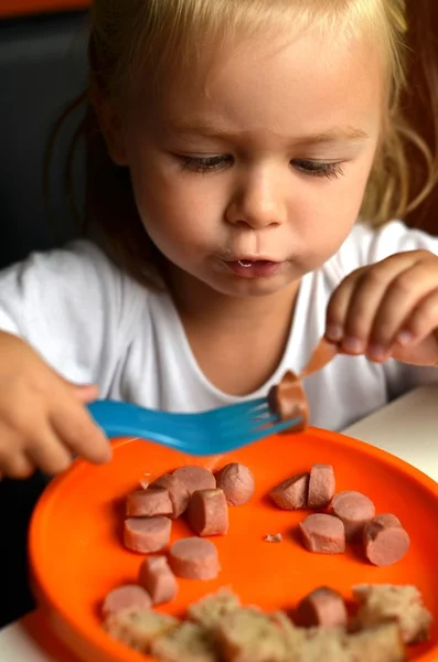 Маленька дівчинка їсть ковбасу — стокове фото
