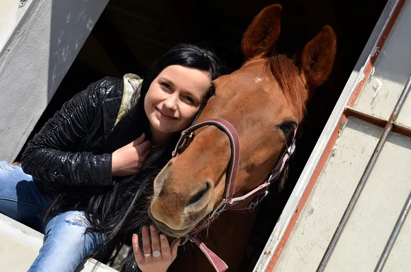Счастливая девушка обнимает коричневую лошадь — стоковое фото