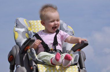 Little baby girl sitting in baby eating chair on nature