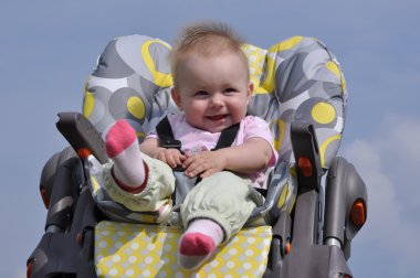 Little baby girl sitting in baby eating chair on nature