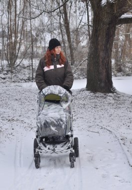 Mother with baby carriage. winter clipart
