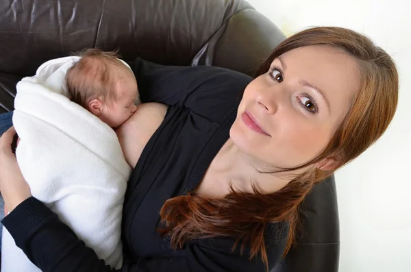 Mutter füttert ihr Neugeborenes mit der Brust - drinnen — Stockfoto
