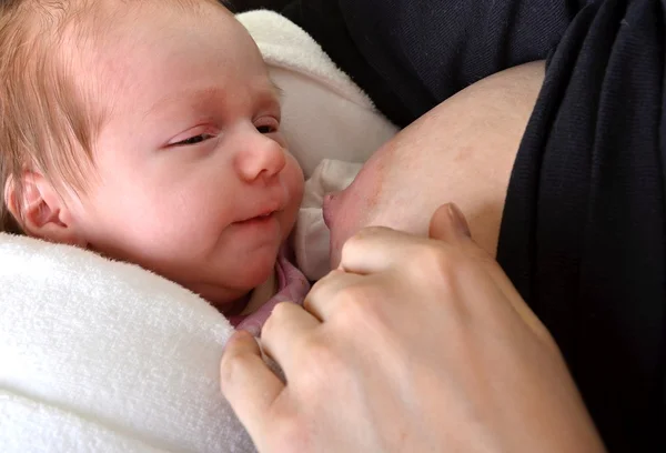Mother feeding her newborn baby with breast - indoors — Stock Photo, Image