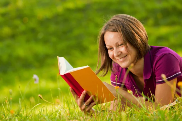 Beautiful woman laughing with a book in the park — Stock Photo, Image
