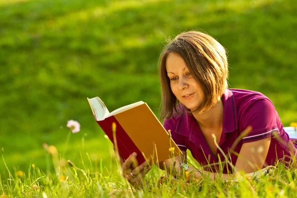 Mooie vrouw die een boek leest in het park — Stockfoto