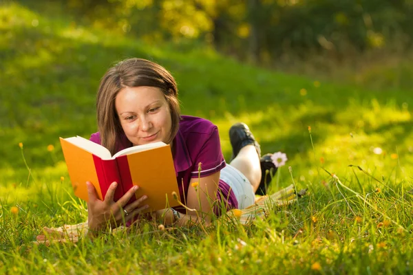 Schöne Frau mit einem Buch im Park — Stockfoto