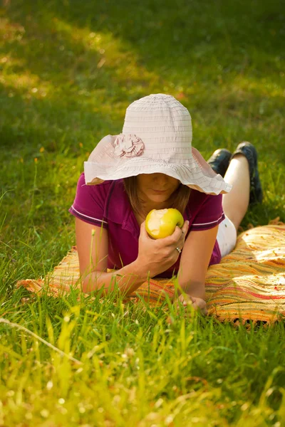 Beautiful woman eating an apple in the park — Stock Photo, Image